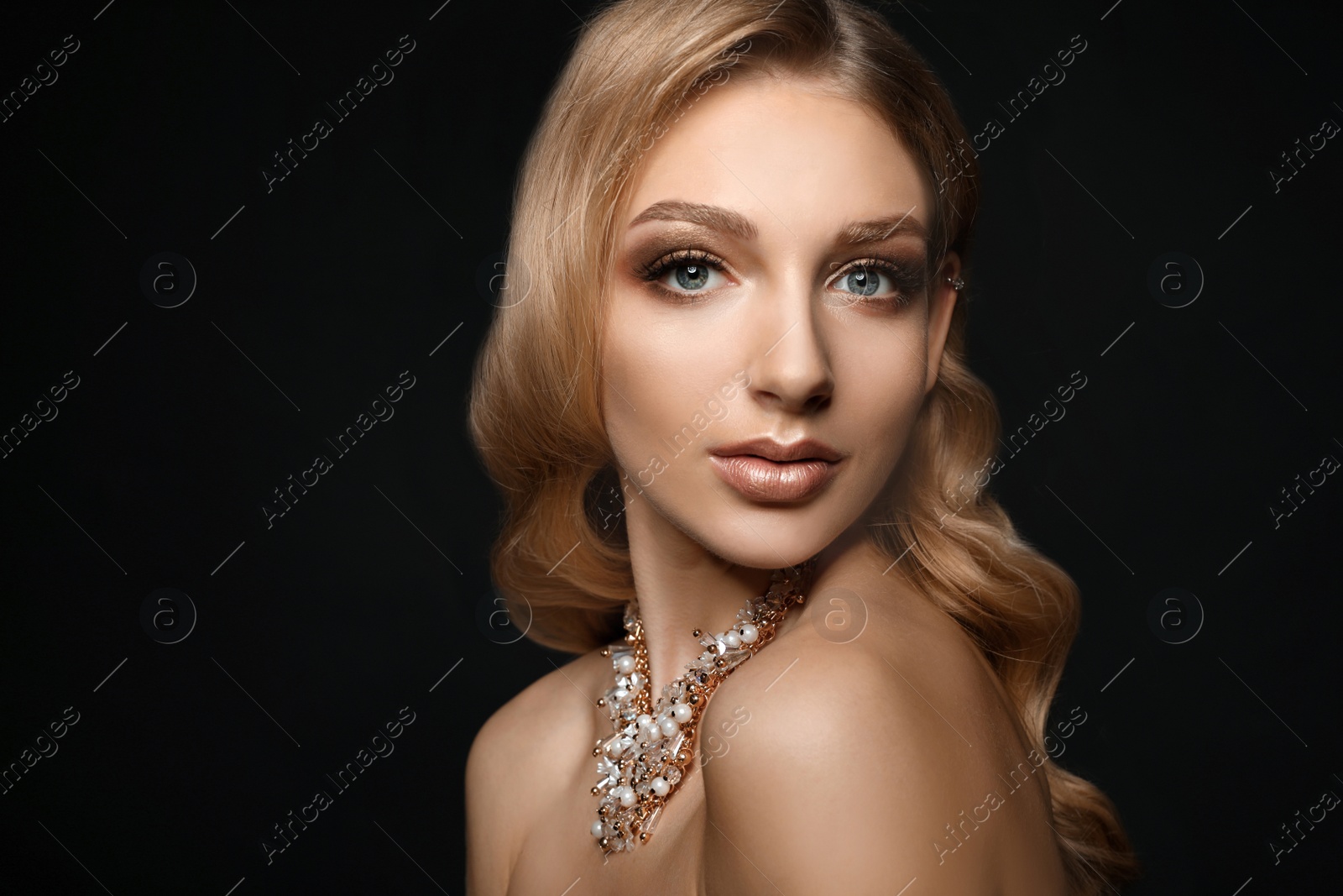 Photo of Beautiful young woman with elegant jewelry on dark background