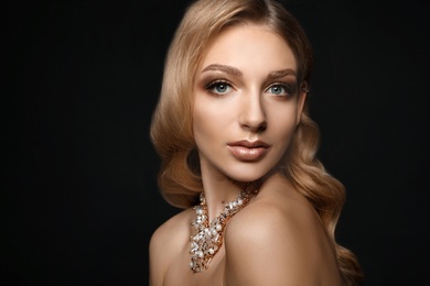 Photo of Beautiful young woman with elegant jewelry on dark background
