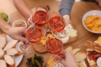 People clinking glasses with rose wine at wooden table, above view