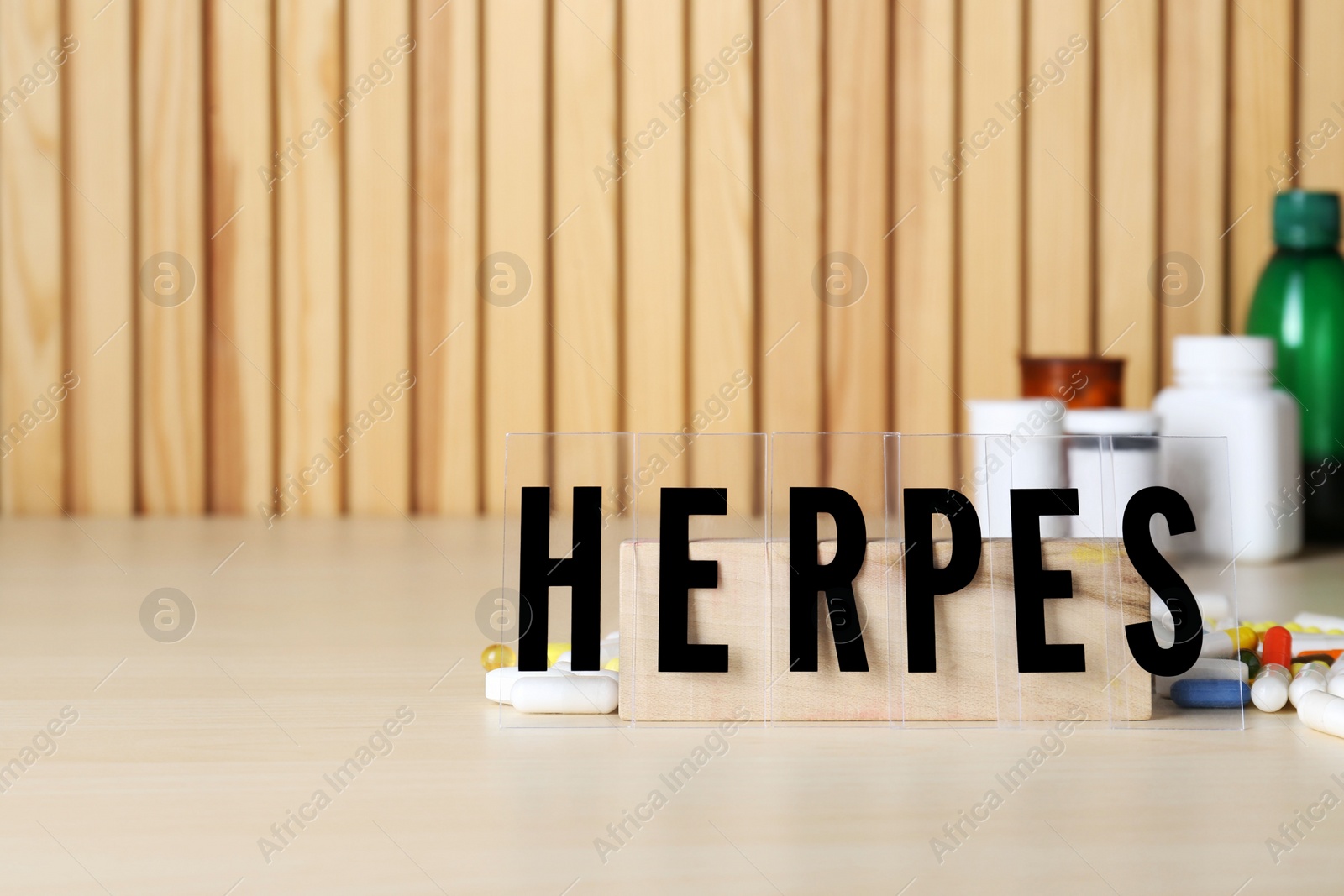 Photo of Word Herpes and different pills on wooden table. Space for text
