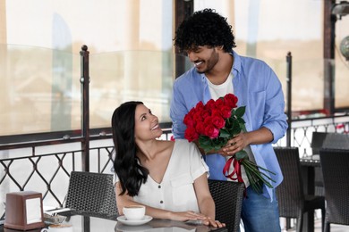 Photo of International dating. Handsome man presenting roses to his girlfriend in restaurant