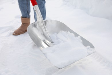 Photo of Woman removing snow with shovel outdoors, closeup