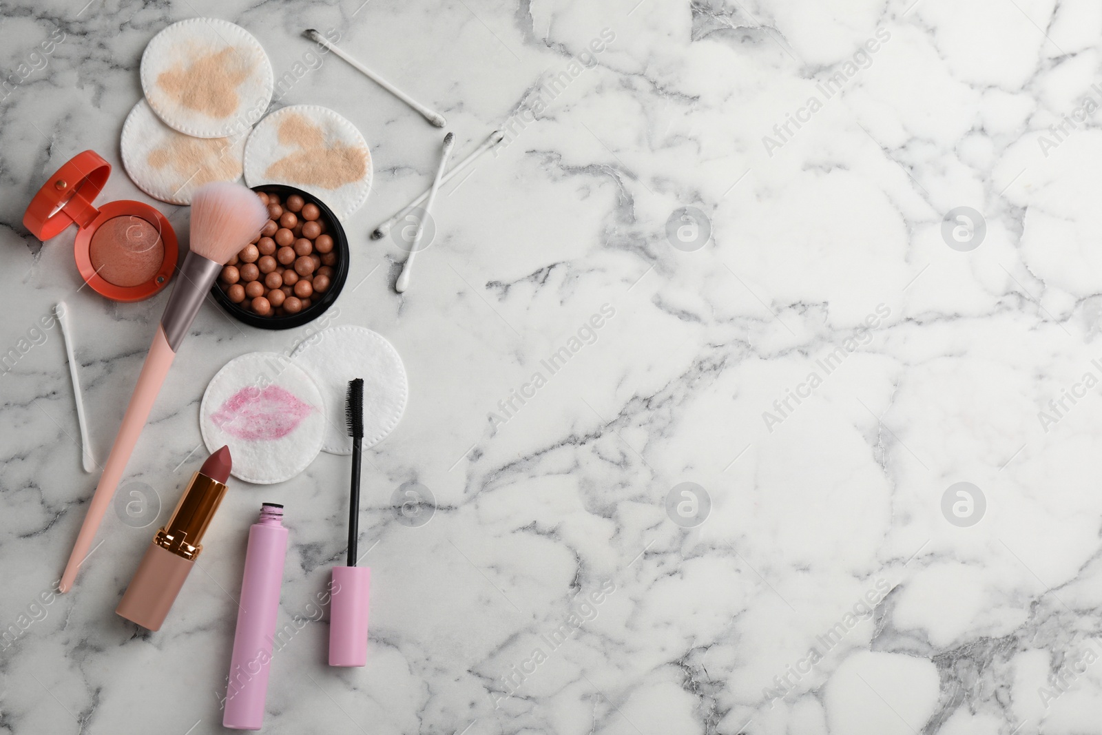 Photo of Dirty cotton pads, swabs and cosmetic products on white marble background, flat lay. Space for text