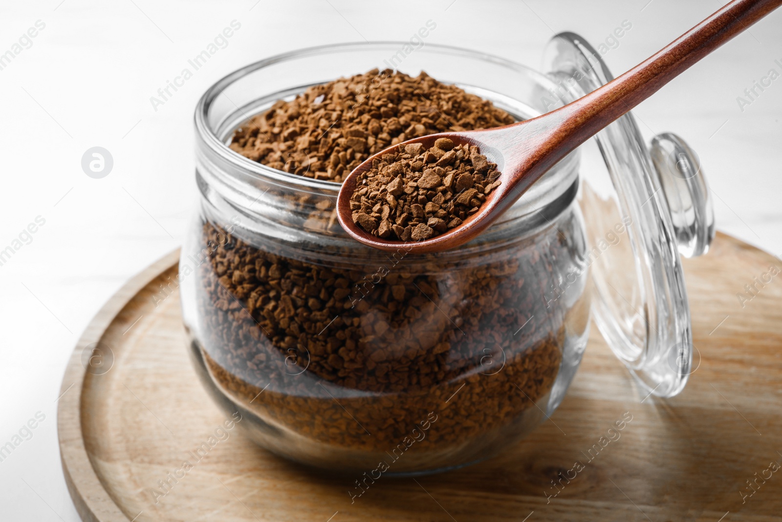 Photo of Jar of instant coffee and spoon on white table, closeup