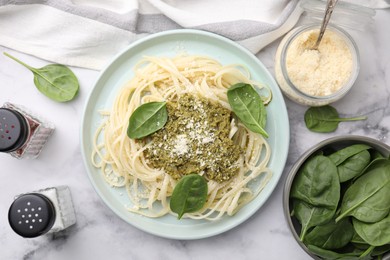 Photo of Tasty pasta with spinach, cheese and sauce on white marble table, flat lay