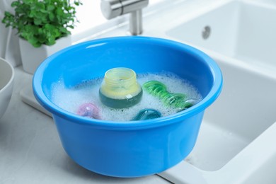 Light blue basin with baby bottles on white countertop in kitchen