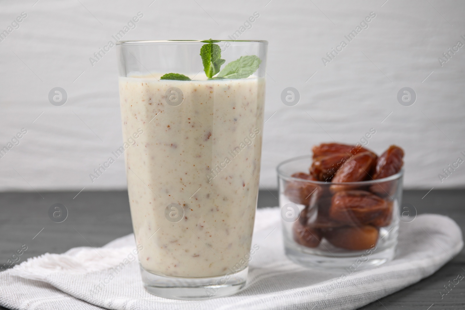 Photo of Glass of delicious date smoothie with mint and dried fruits on grey table, closeup. Space for text