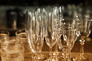 Photo of Different empty clean glasses on counter in bar, closeup