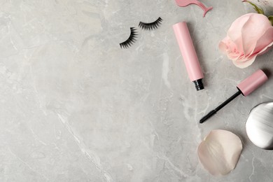 Photo of Mascara, fake eyelashes and flower on light background, flat lay with space for text. Makeup product