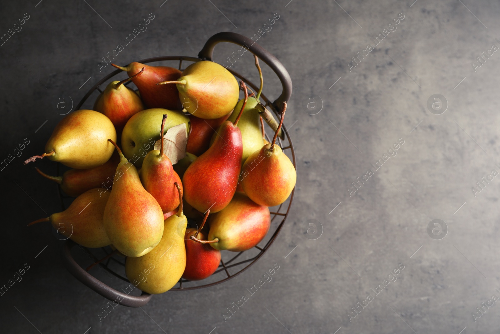 Photo of Basket with ripe pears on grey background, top view. Space for text