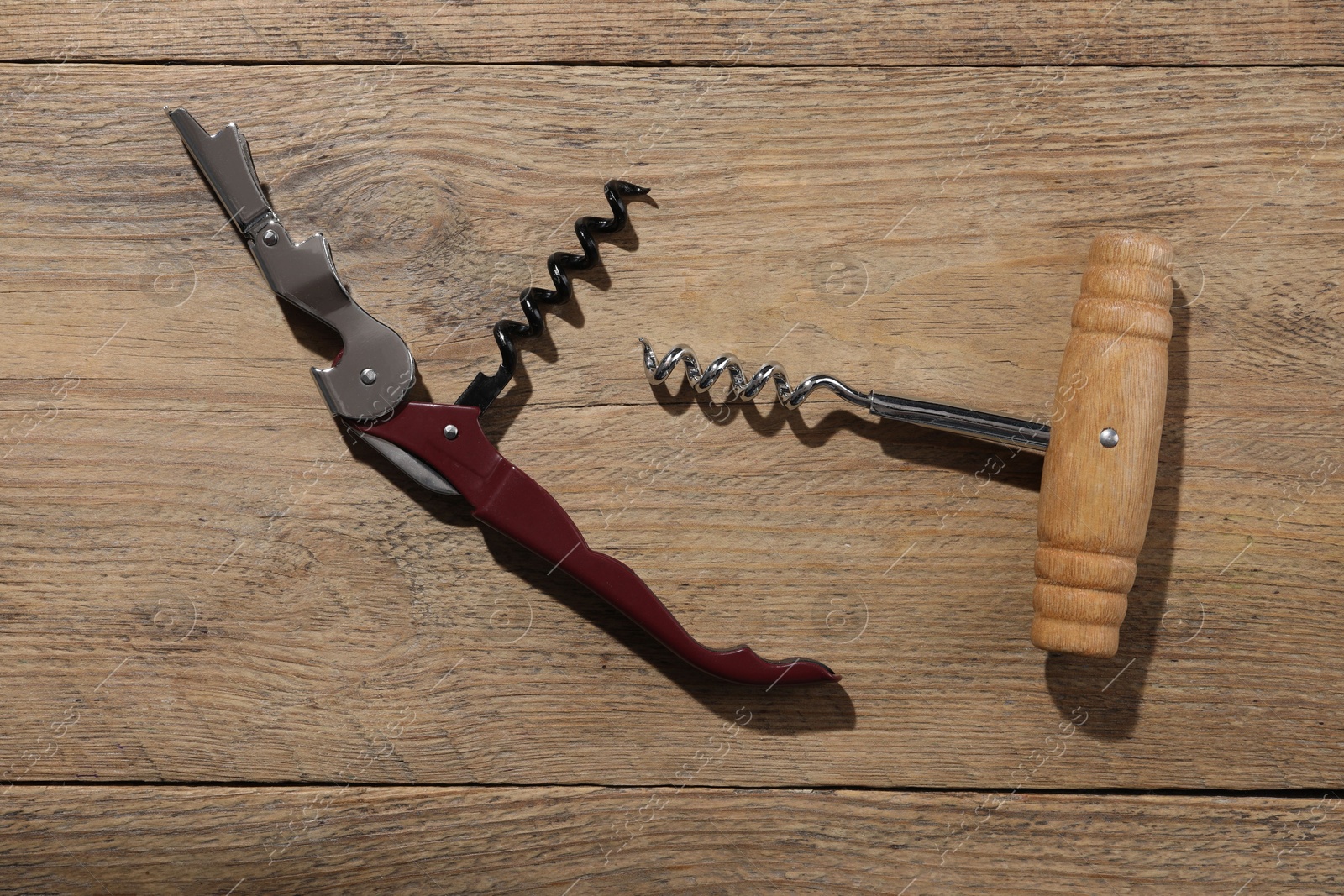 Photo of Different corkscrews on wooden table, flat lay