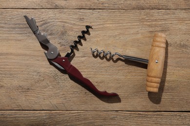 Photo of Different corkscrews on wooden table, flat lay