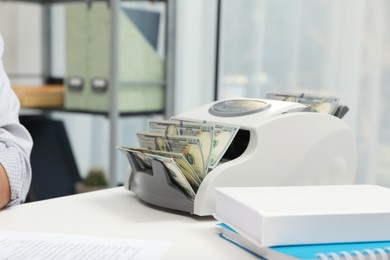 Photo of Modern banknote counter with money on white table indoors