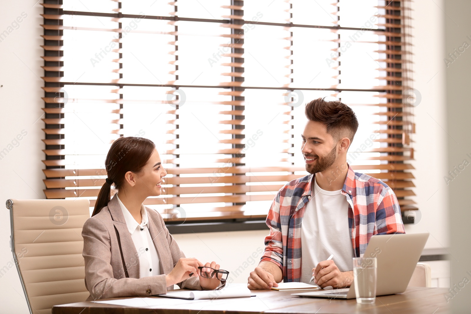 Photo of Female insurance agent consulting young man in office