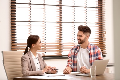 Photo of Female insurance agent consulting young man in office