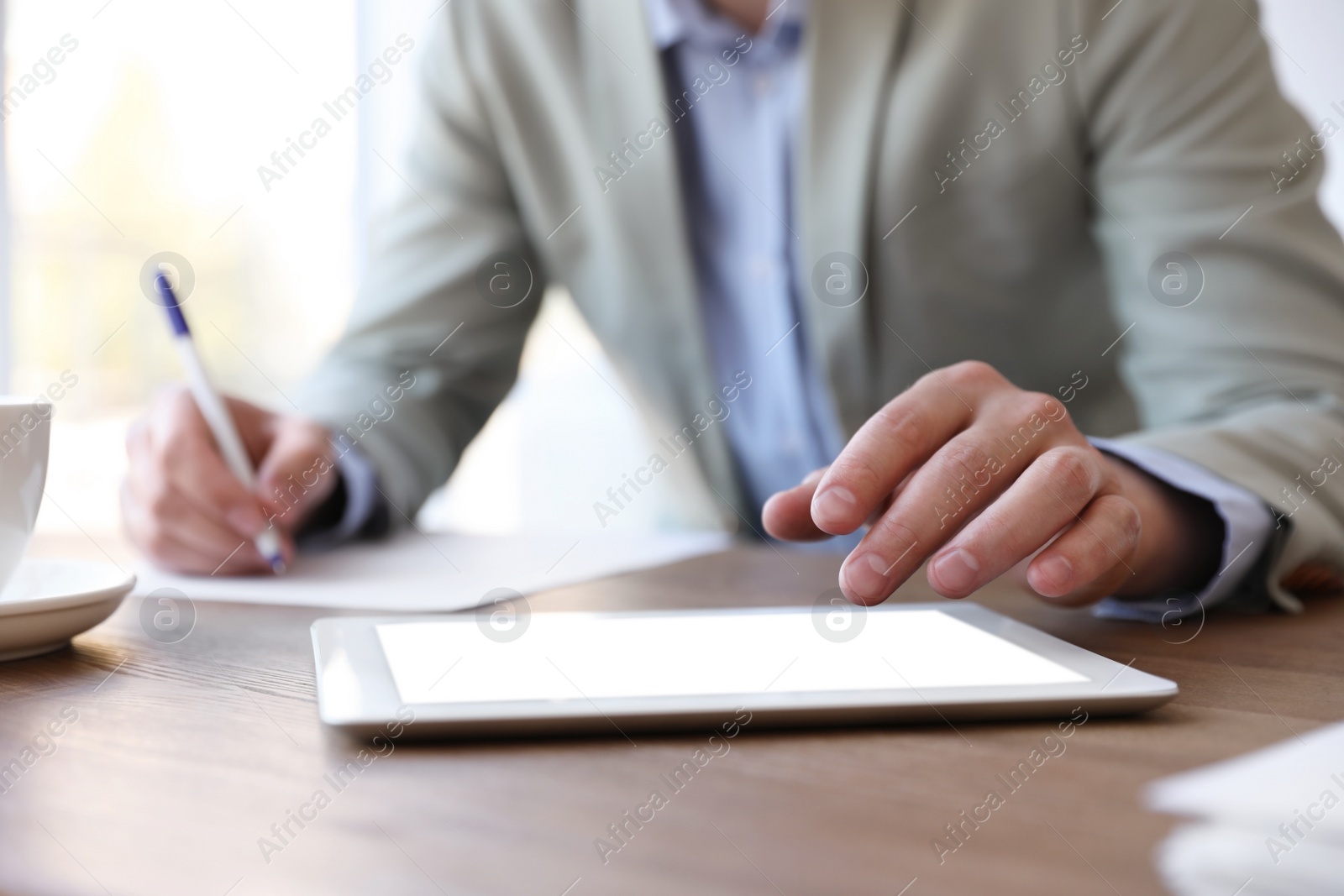 Photo of Businessman working with modern tablet at wooden table in office, closeup