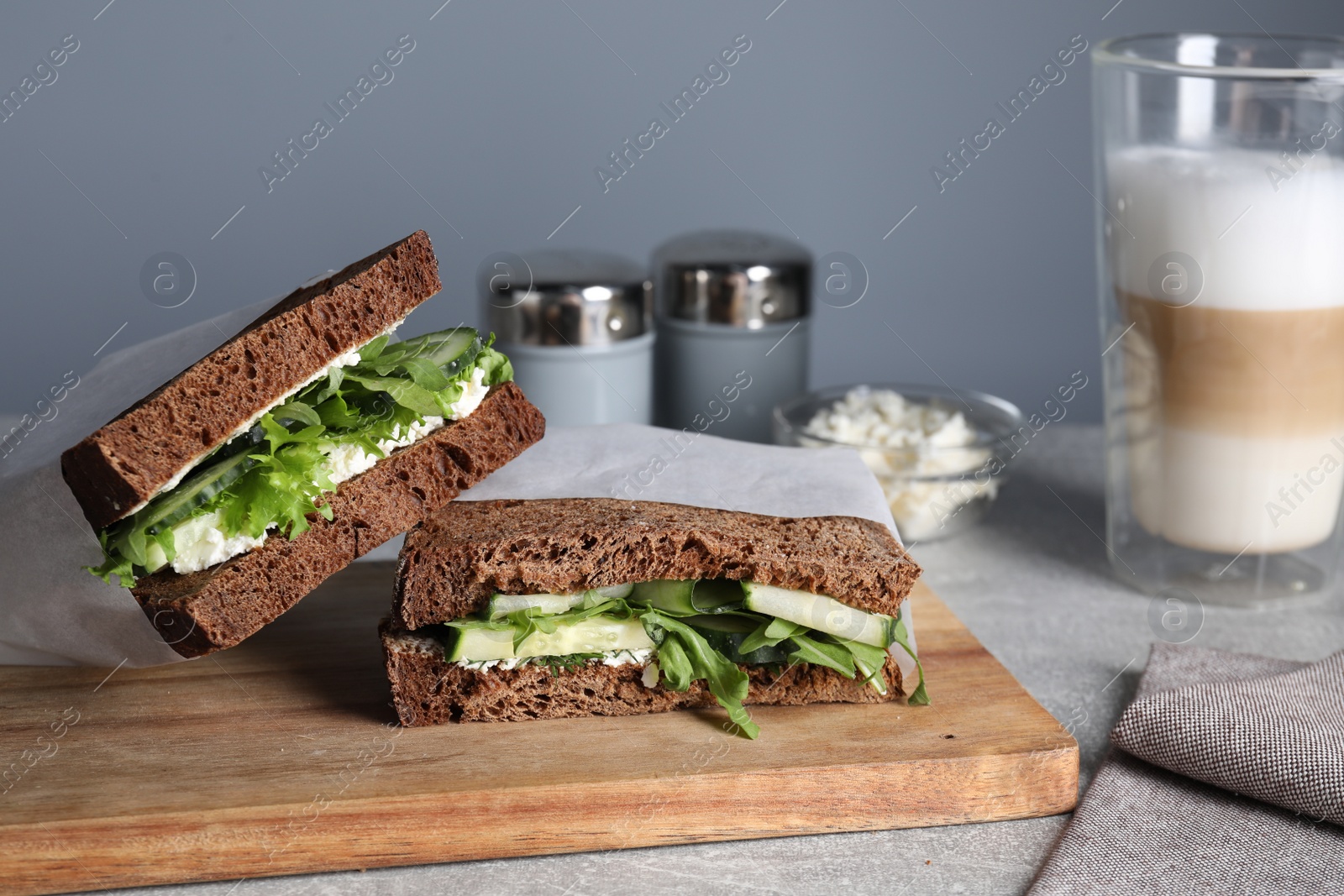 Photo of Tasty sandwiches with cream cheese, cucumber and greens on light grey table