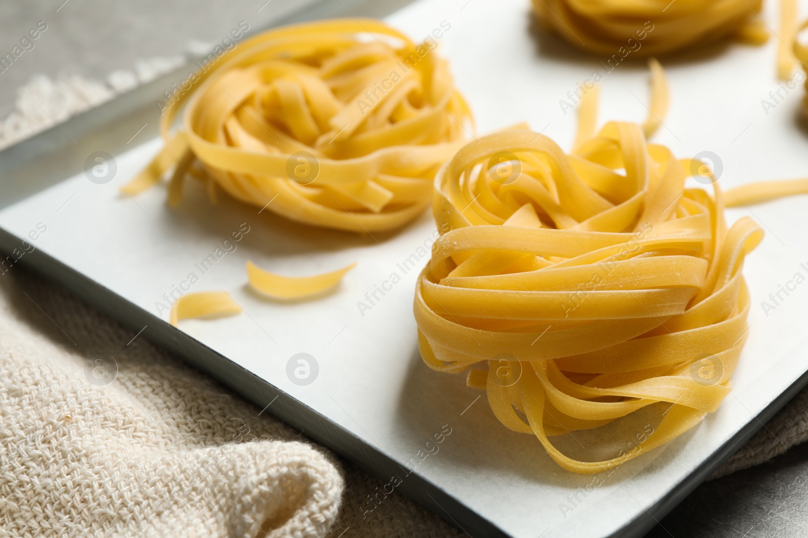 Photo of Raw tagliatelle pasta in baking pan, closeup view