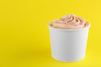 Cup with tasty frozen yogurt on yellow background. Space for text