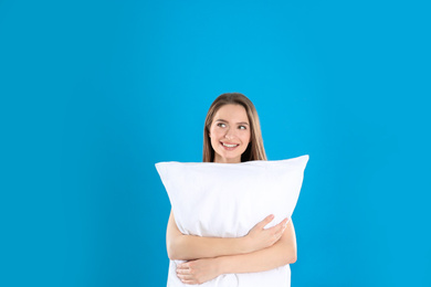 Young woman with pillow on blue background