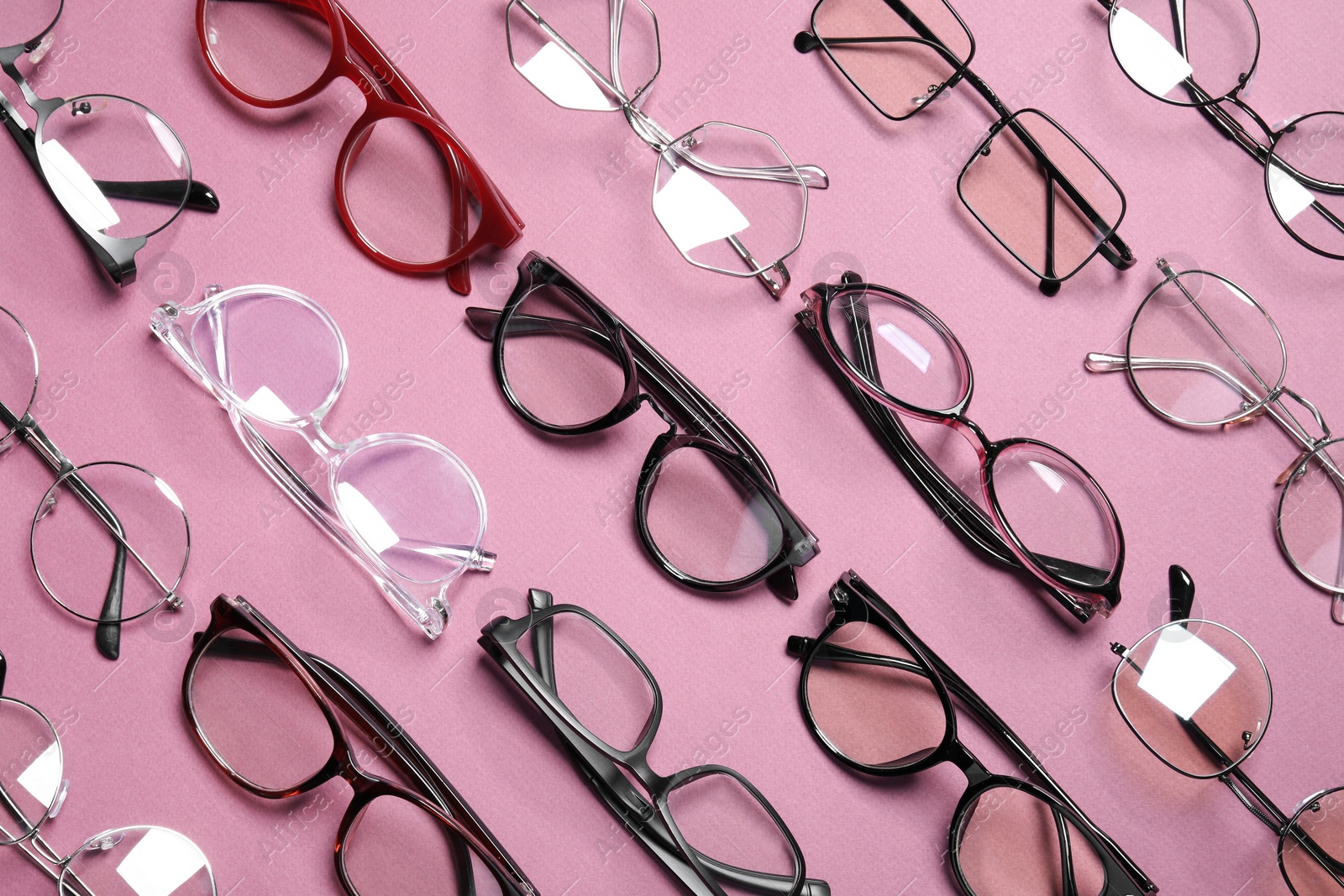 Photo of Different stylish glasses on pink background, flat lay