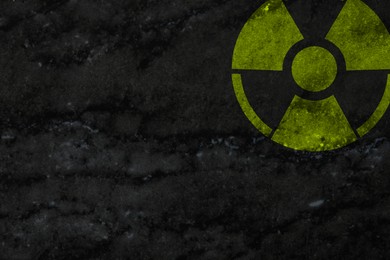 Radioactive sign on dark marble wall, space for text. Hazard symbol