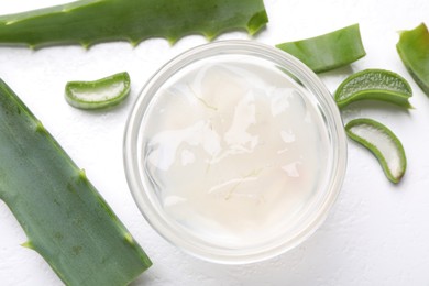 Photo of Aloe vera gel and slices of plant on white background, flat lay