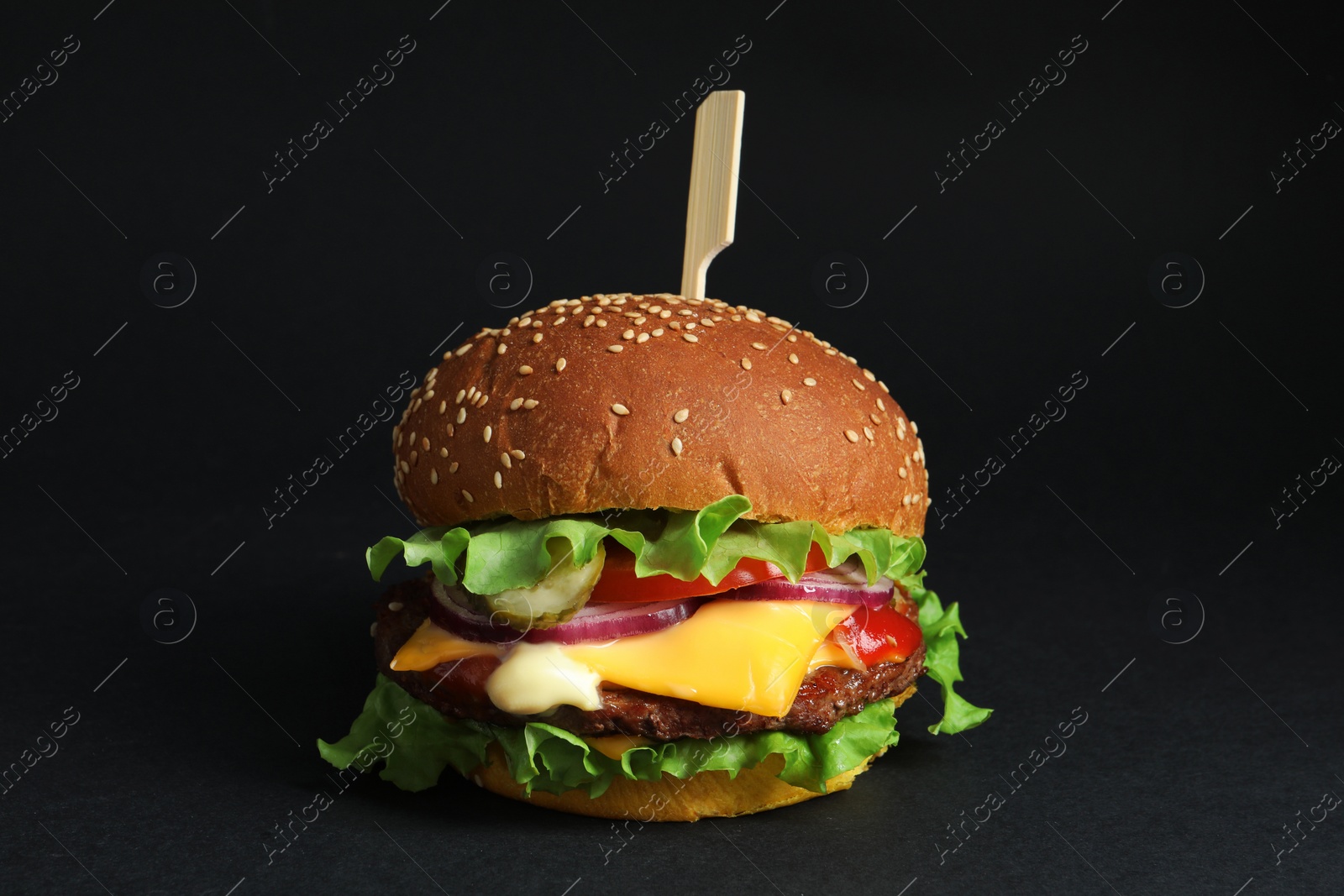 Photo of Delicious burger with beef patty and lettuce on black background