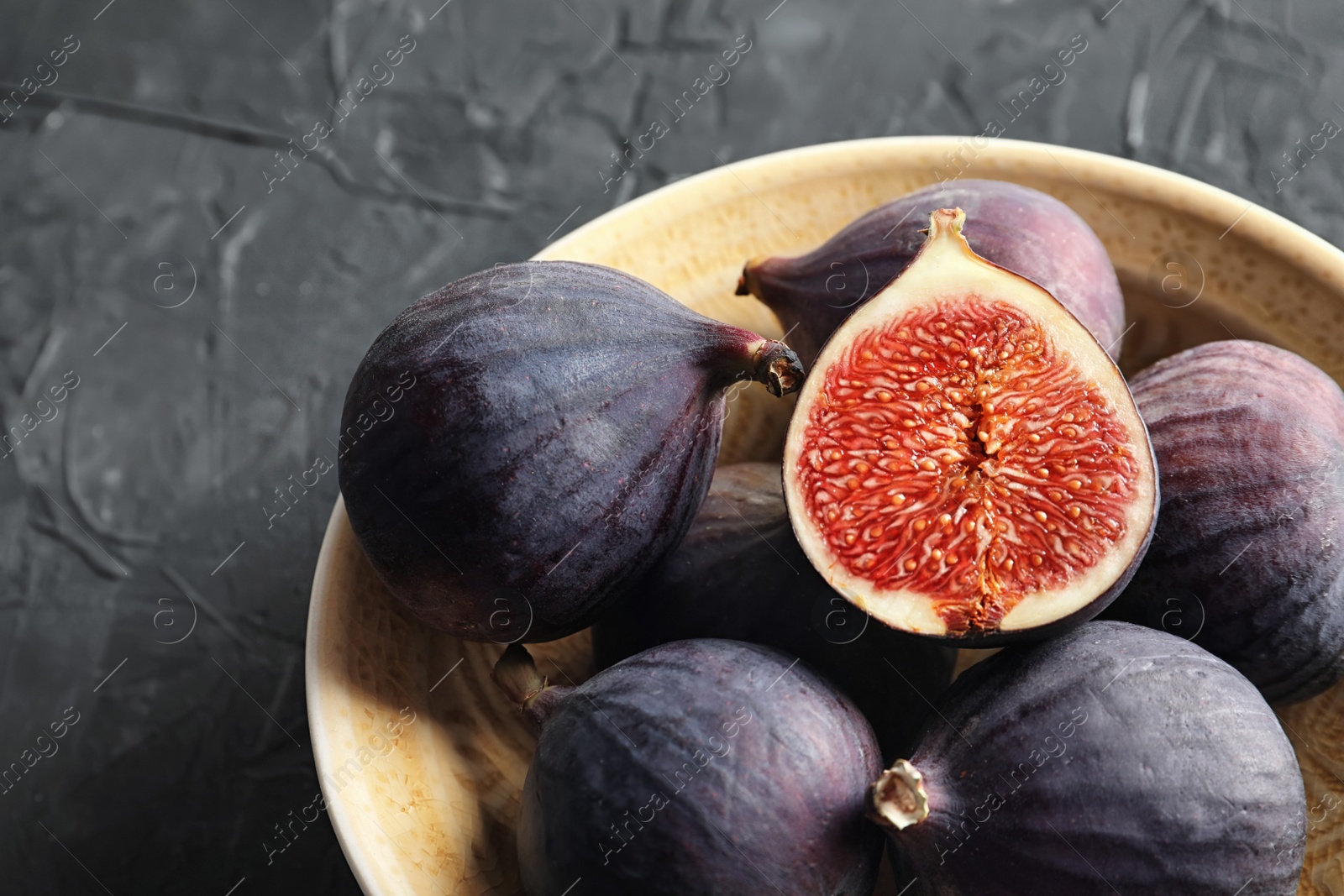 Photo of Bowl with fresh ripe figs on dark background. Tropical fruit