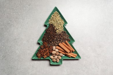 Different spices and nuts on light gray textured table, top view