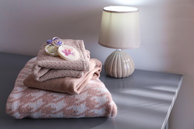 Photo of Stack of clothes with beautiful scented wax sachets on grey table indoors