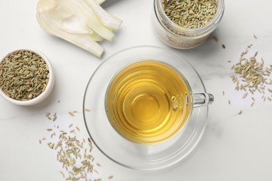 Photo of Aromatic fennel tea, seeds and fresh vegetable on white table, flat lay