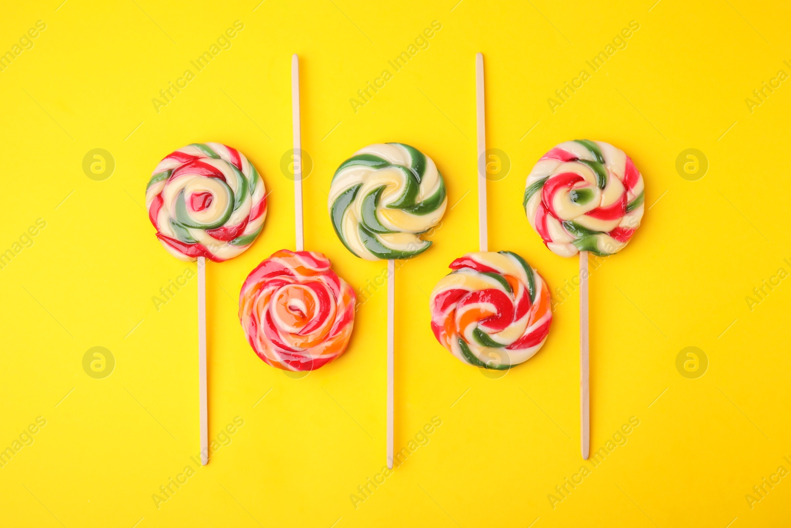 Photo of Many colorful lollipops on yellow background, flat lay