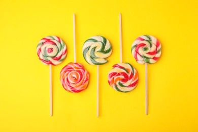 Photo of Many colorful lollipops on yellow background, flat lay