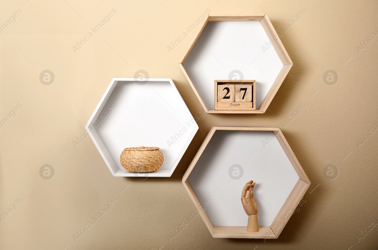 Photo of Honeycomb shaped shelves with decorative elements on beige wall