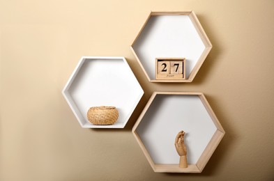 Photo of Honeycomb shaped shelves with decorative elements on beige wall