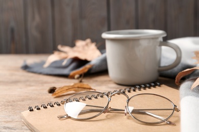 Photo of Notebook and glasses on wooden table, closeup. Space for text