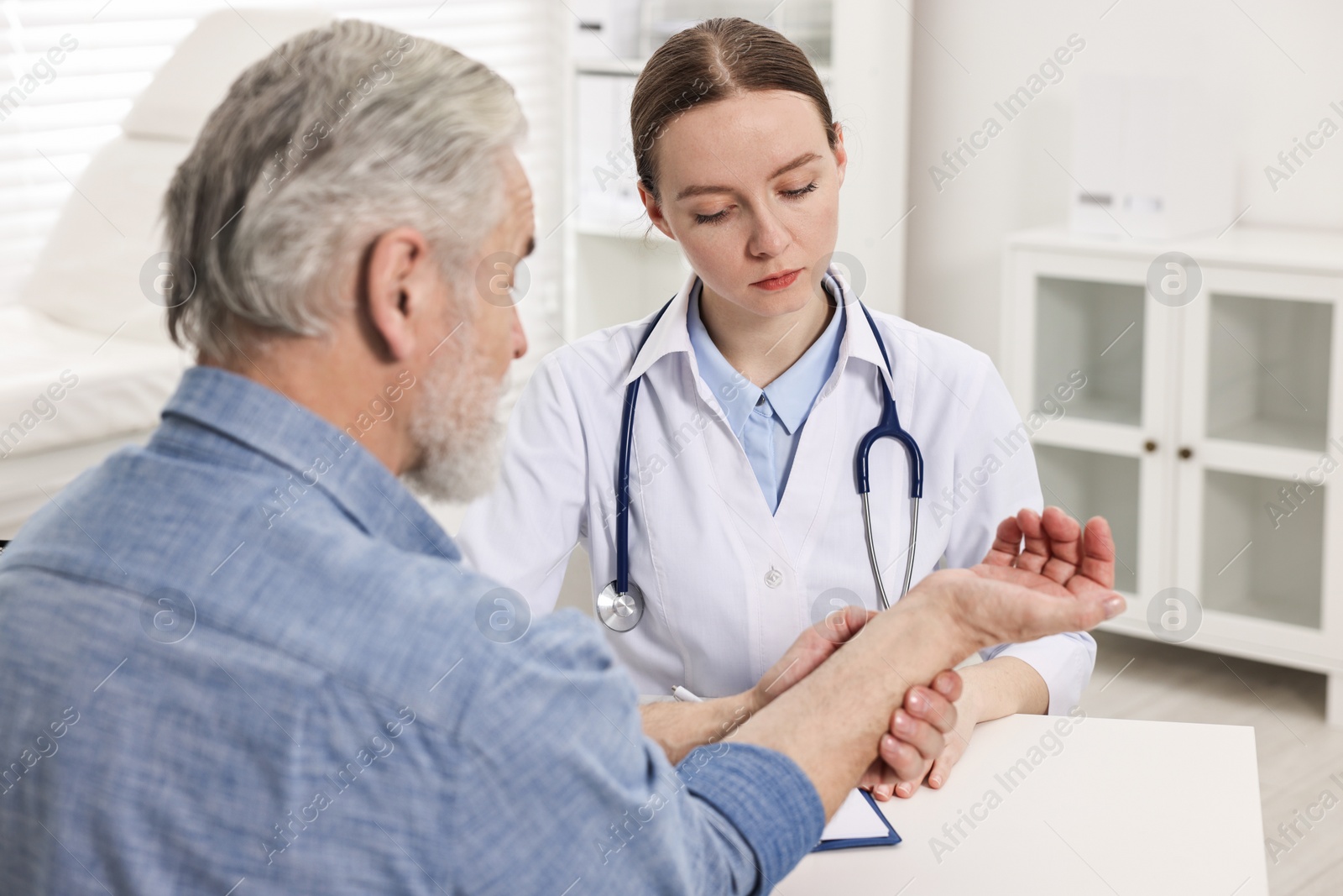 Photo of Arthritis symptoms. Doctor examining patient's wrist in hospital