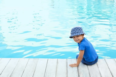 Photo of Little child near outdoor swimming pool. Dangerous situation