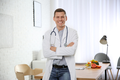 Nutritionist with stethoscope near desk in office