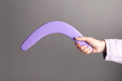 Woman holding boomerang on grey background, closeup