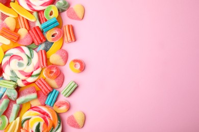 Photo of Many different jelly candies and lollipops on pink background, flat lay. Space for text