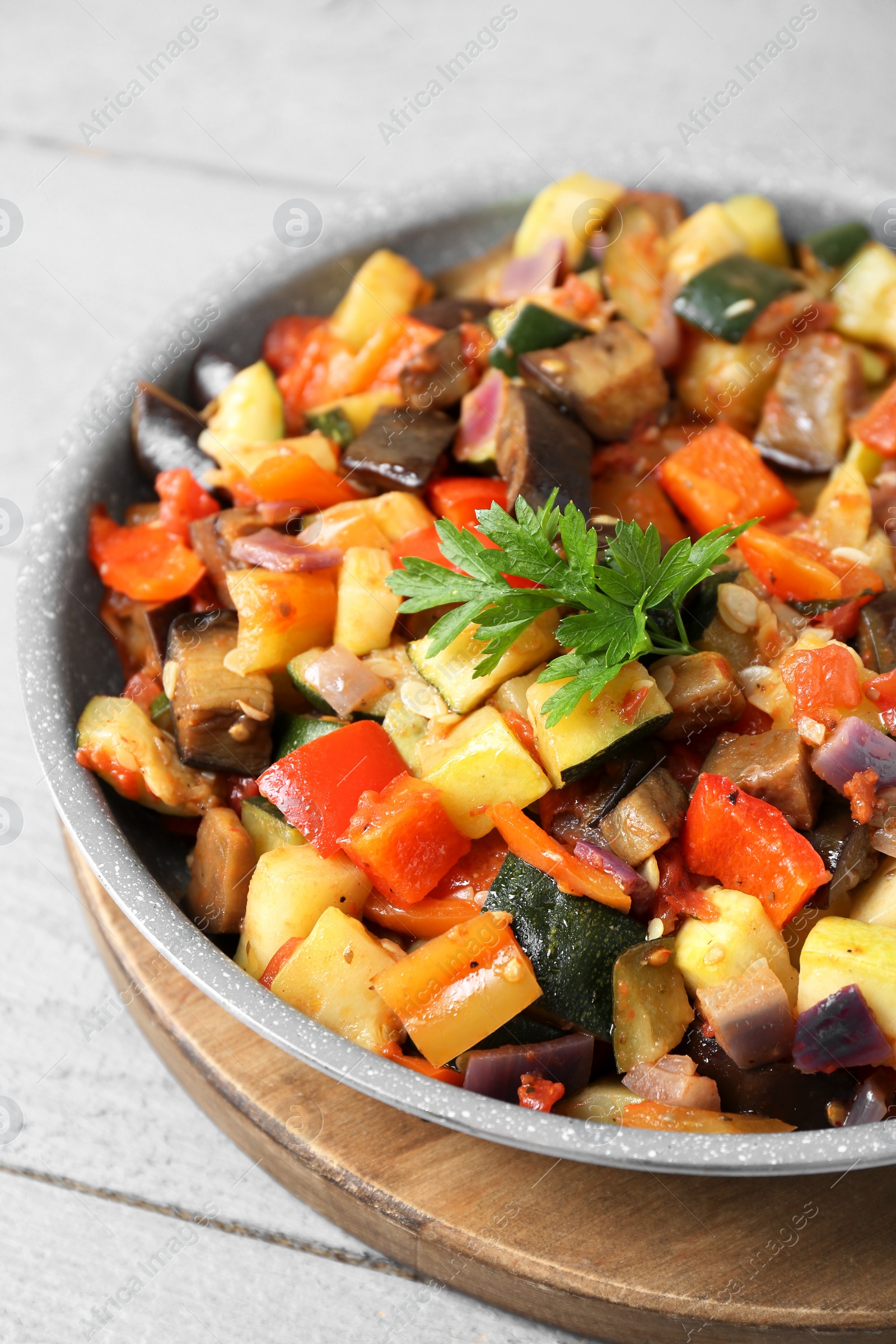 Photo of Delicious ratatouille in frying pan on grey wooden table, closeup