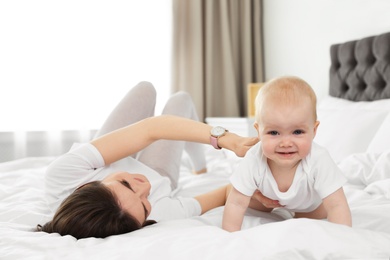 Photo of Adorable little baby crawling near mother on bed indoors