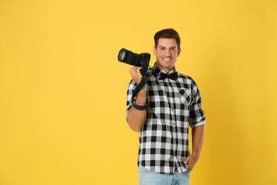 Photo of Professional photographer working on yellow background in studio. Space for text