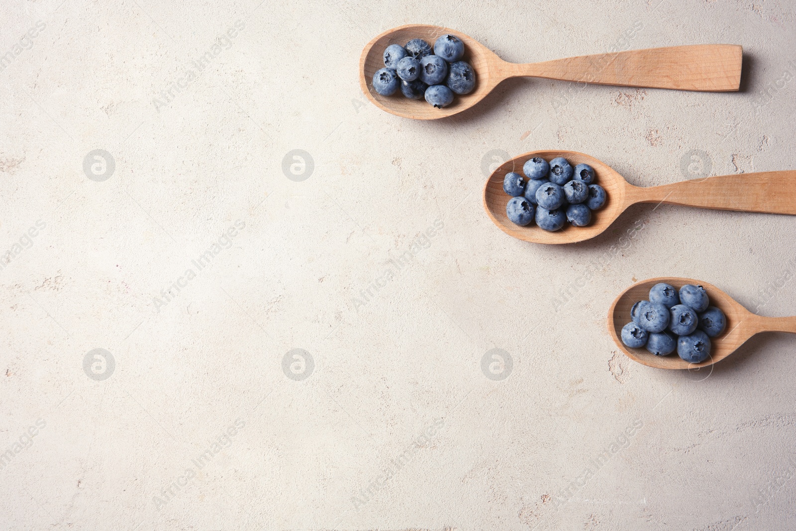 Photo of Flat lay composition with spoons and juicy blueberries on color table. Space for text