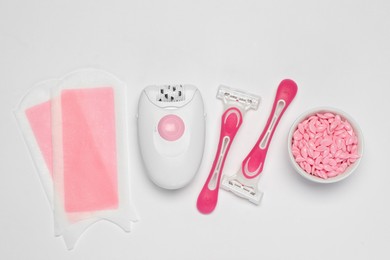 Photo of Modern epilator and other hair removal products on white background, flat lay