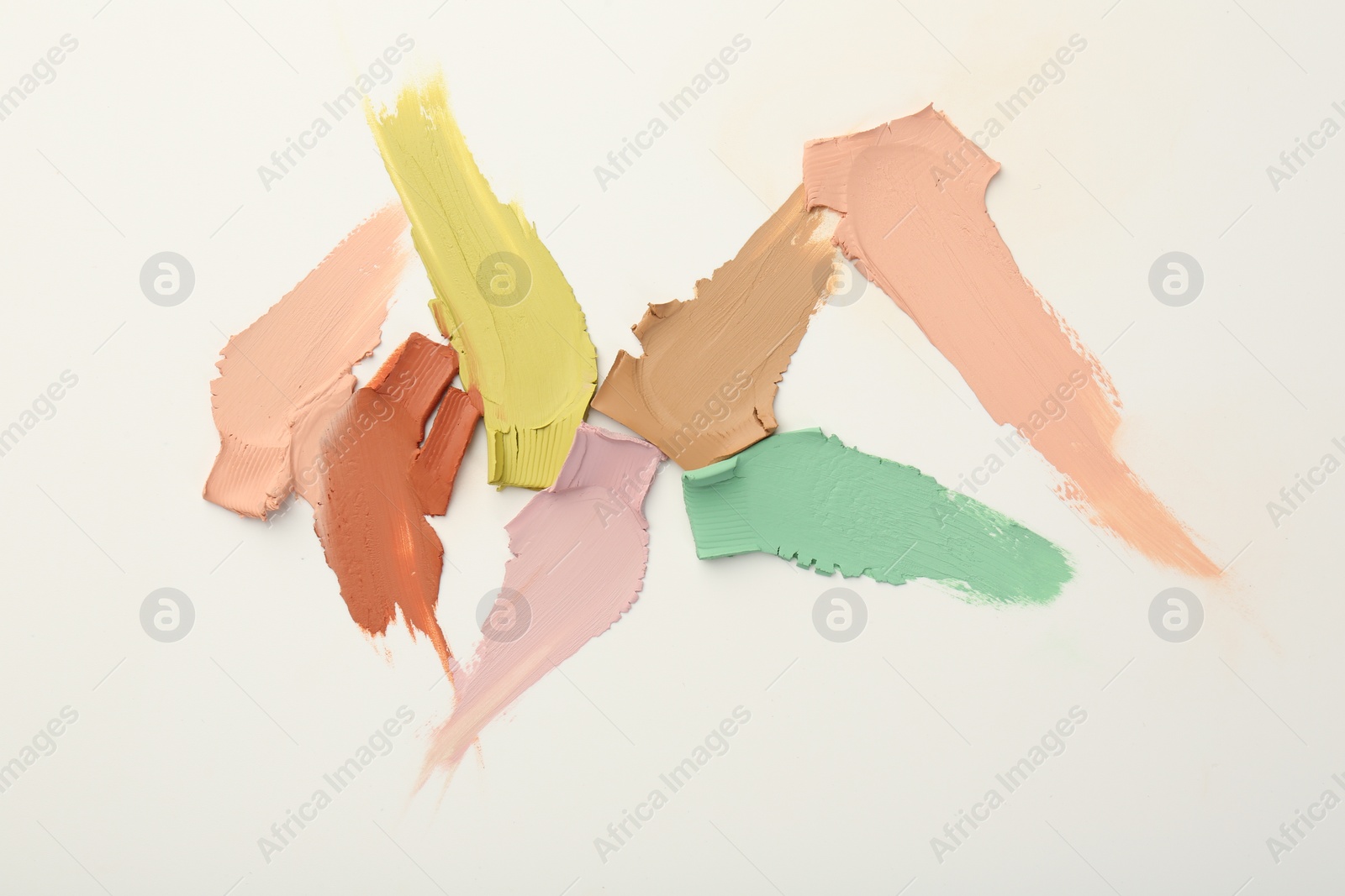 Photo of Samples of different color correcting concealers on white background, top view