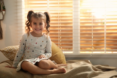Photo of Portrait of cute little girl near window at home