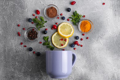 Cup and ingredients for immunity boosting tea on grey table, flat lay